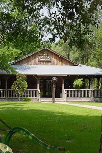 乡村橡树房车公园和露营地——一栋温馨的木质建筑，坐落在郁郁葱葱的绿色草坪上。