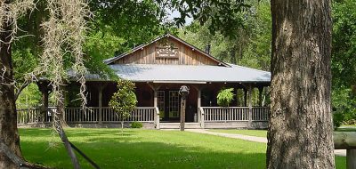 乡村橡树房车公园和露营地——一栋温馨的木质建筑，坐落在郁郁葱葱的绿色草坪上。